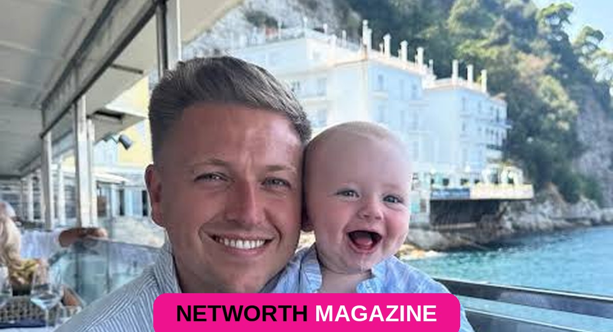 Simon Wilson smiling while holding a baby during a trip abroad